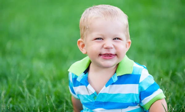 Αστείο μικρό αγόρι πάνω από το πράσινο γρασίδι — Φωτογραφία Αρχείου
