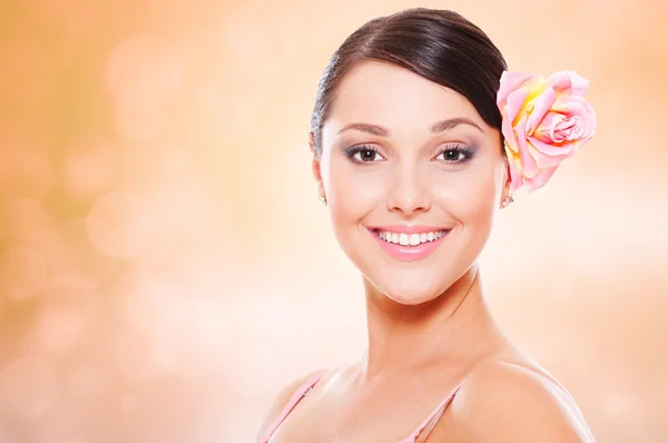 Jolie modèle souriant avec rose dans les cheveux — Photo