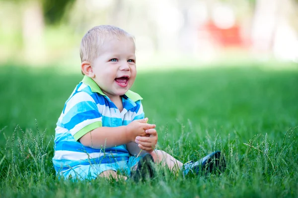 Мальчик сидит на лужайке и играет — стоковое фото