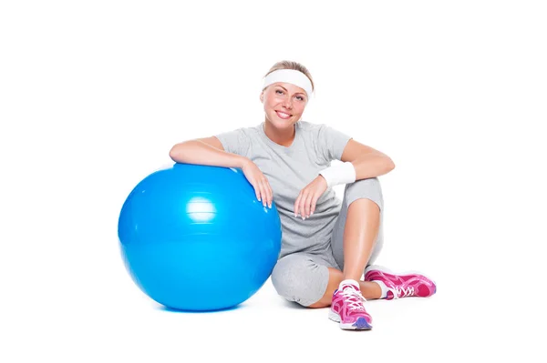 Kvinna sitter nära blå bollen och leende — Stockfoto