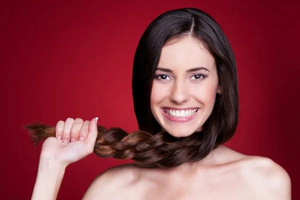 Женщина держит косу и улыбается — стоковое фото