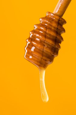 Spoon of honey on a colored background clipart