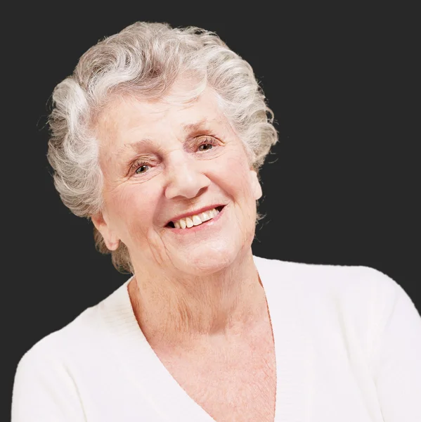 Äldre kvinna ler mot en svart bakgrund — Stockfoto