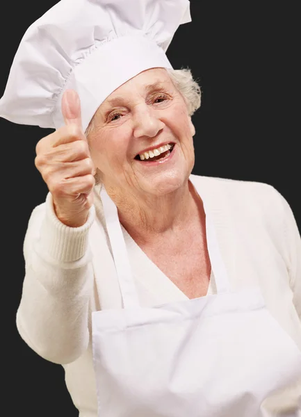 Portrait de cuisinière senior faisant geste d'approbation sur noir — Photo