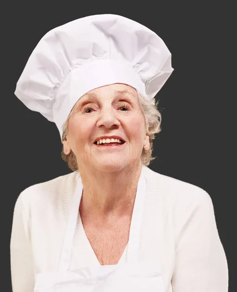 Старший повар женщина улыбается на черном фоне — стоковое фото