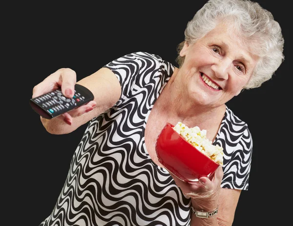 Retrato de mulher idosa feliz olhando a tv sobre backgro preto — Fotografia de Stock