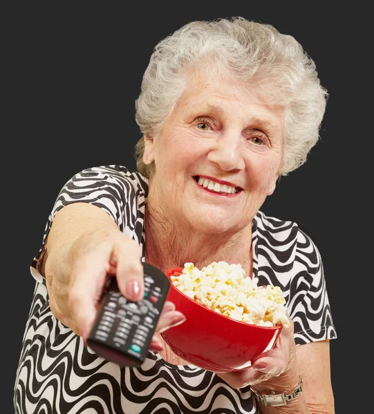Portrait of senior woman holding pop corn bowl and changing chan — Stock Photo, Image