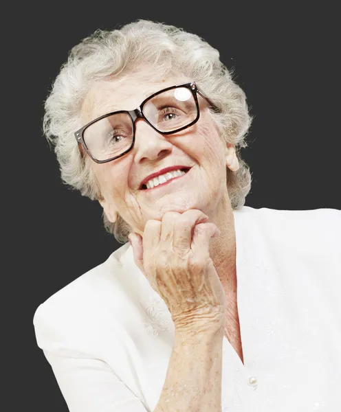 Porträt einer Seniorin, die über den schwarzen Rücken nachdenkt und nach oben blickt — Stockfoto