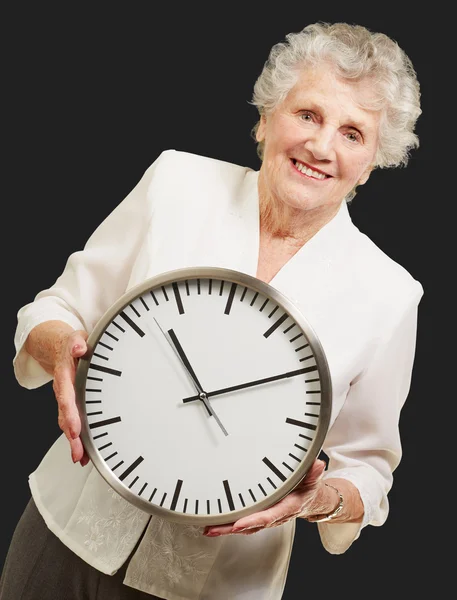 Портрет счастливой пожилой женщины, держащей часы над черным — стоковое фото
