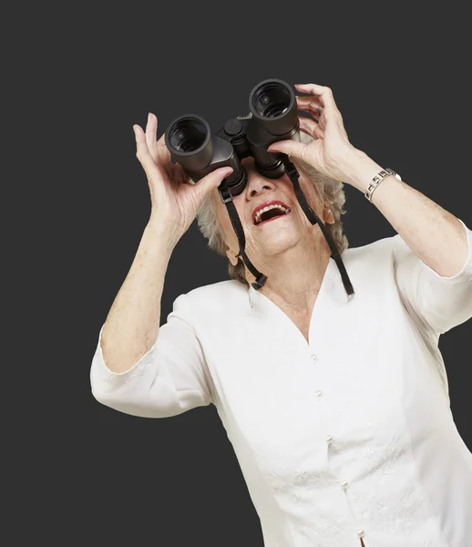 Portret van senior vrouw kijken door een verrekijker tegen een — Stockfoto