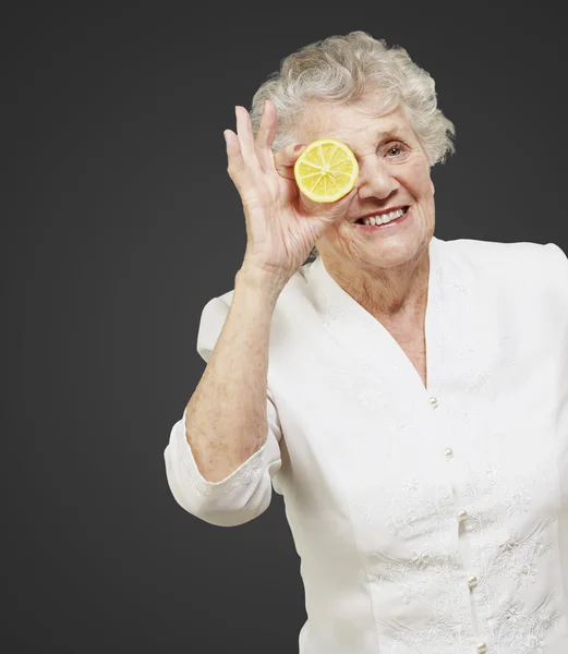 Portrait de femme âgée avec du citron devant l "œil sur bla — Photo