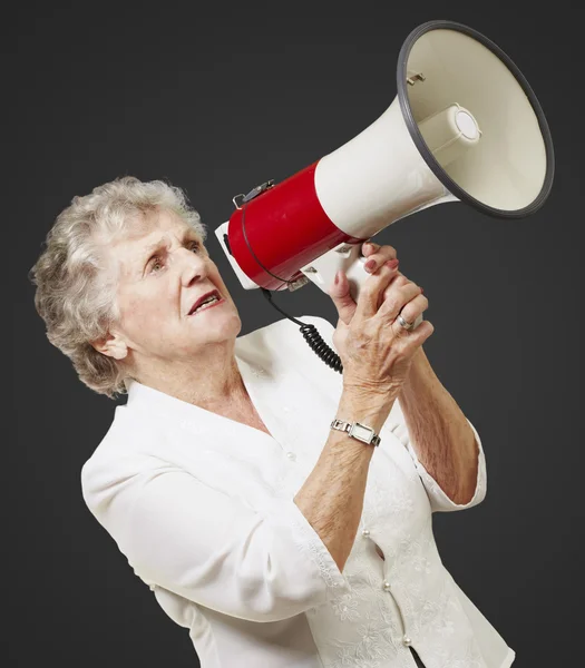 Ritratto di donna anziana che tiene il megafono su sfondo nero — Foto Stock