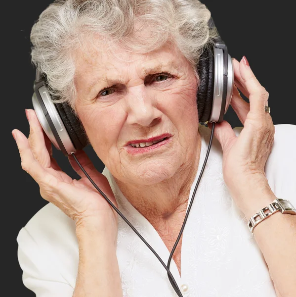 Portrait of senior woman listening to music over black — Stock Photo, Image