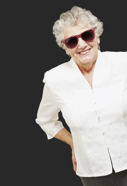 Porträtt av äldre kvinna stående bär solglasögon över svart — Stockfoto