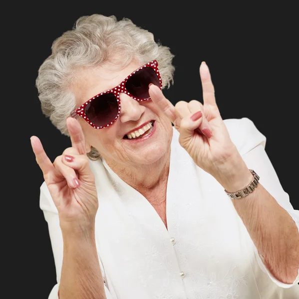 Портрет счастливой пожилой женщины, изображающей рок-символ над черной бабой — стоковое фото
