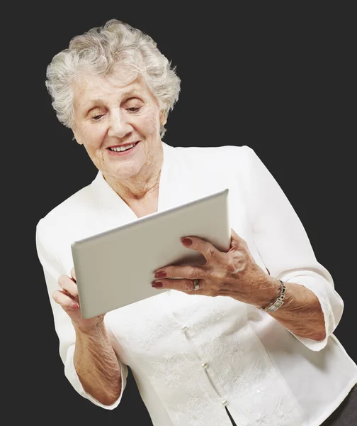 Portret senior kobiety dotykając cyfrowe tabletki na tył czarny — Zdjęcie stockowe