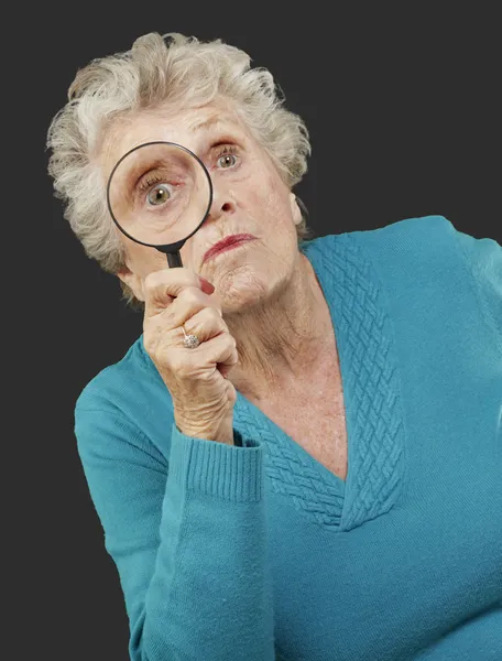 Retrato de una mujer mayor mirando a través de una lupa — Foto de Stock