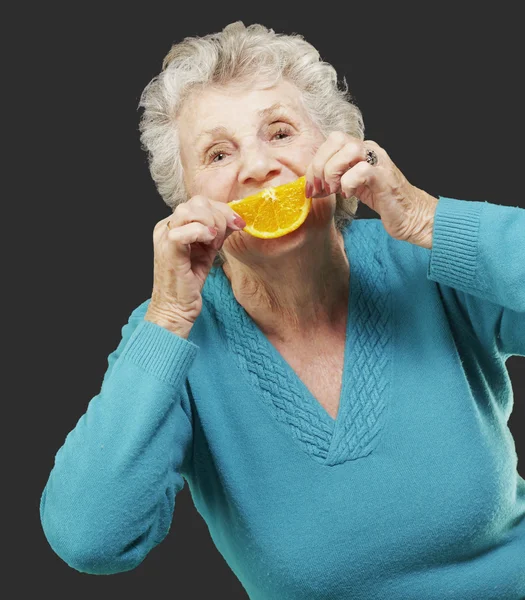 彼女の前にオレンジ スライスを保持している年配の女性の肖像画 — ストック写真