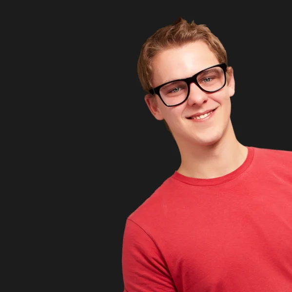 Portret młodzieńca uśmiechający się noszenie okularów na czarny backgro — Zdjęcie stockowe