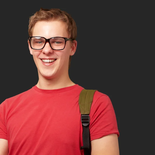 Portrait of young man holding laptop and wearing backpack over b — Stock Photo, Image