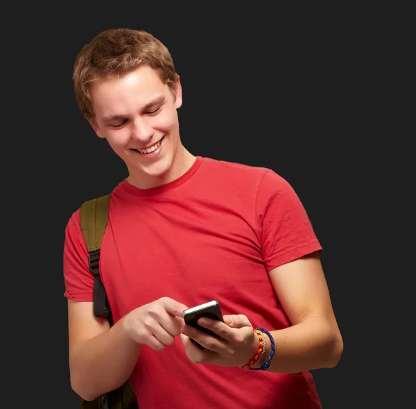 Portrét mladého muže dotknete mobilní obrazovky nad černou poz — Stock fotografie