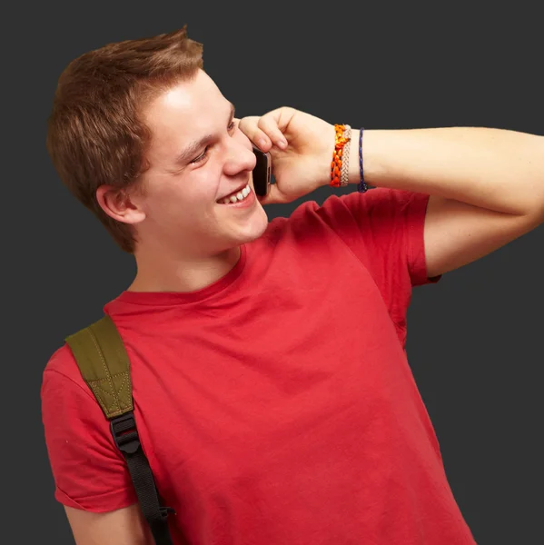 黒の背景上の携帯電話で話している若い男の肖像 — ストック写真