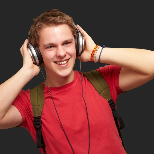 Portrait of cheerful young student listening music with headphon — Stock Photo, Image