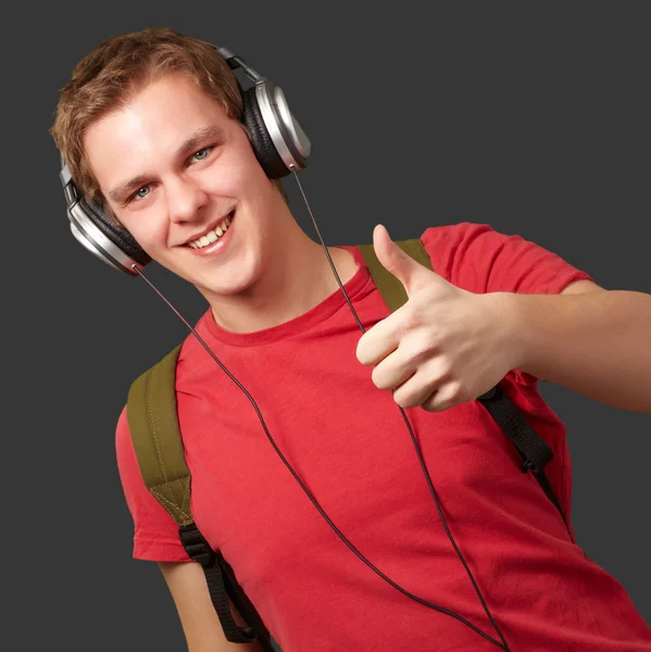 Retrato de un joven estudiante alegre escuchando música y gestos — Foto de Stock