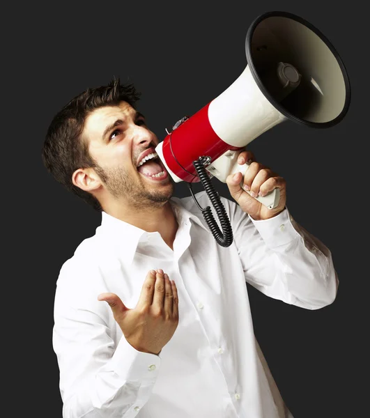 Portret van jonge man schreeuwen met megafoon over zwarte backgro — Stockfoto