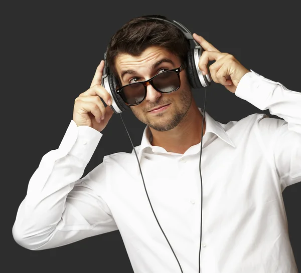 Portrait of young man listening to music using headphones over b — Stock Photo, Image
