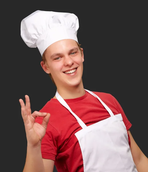 Portret człowieka młody kucharz robi symbol sukcesu przed czarną — Zdjęcie stockowe