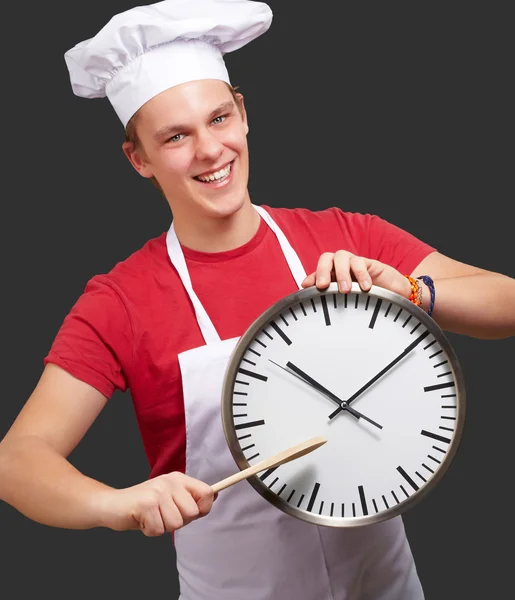 Portret młodej gotować człowieka wskazując zegar nad czarny deseń — Zdjęcie stockowe