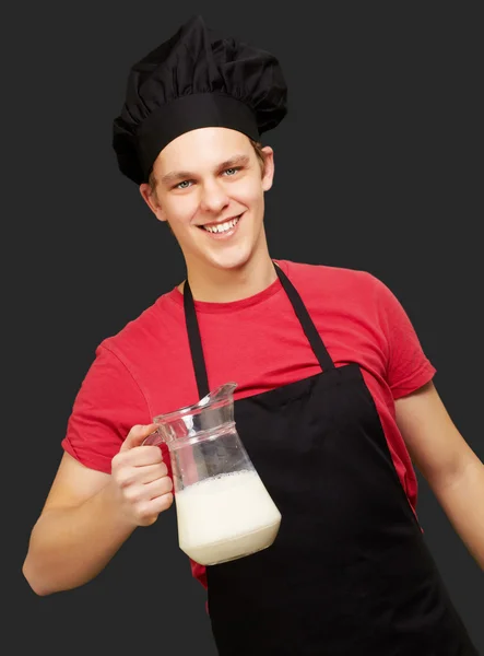 Portret młodej gotować człowieka posiadającego mleka słoik na czarny deseń — Zdjęcie stockowe