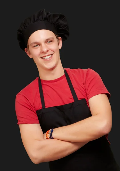 Portret młodej gotować człowieka noszenie munduru i uśmiechając się nad blac — Zdjęcie stockowe