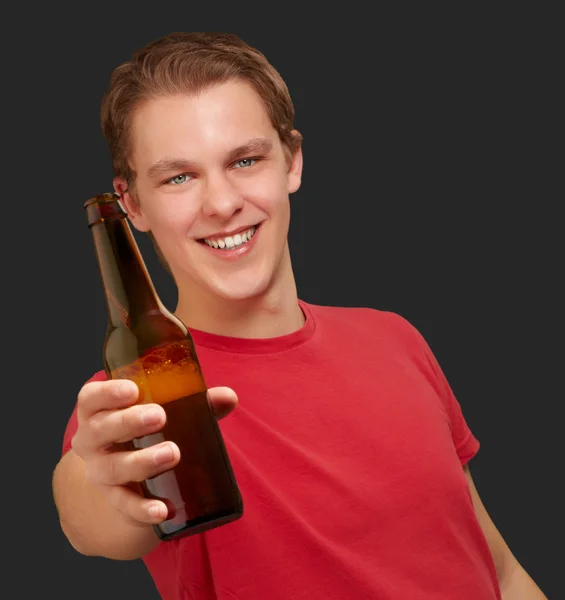Retrato de jovem segurando cerveja sobre fundo preto — Fotografia de Stock