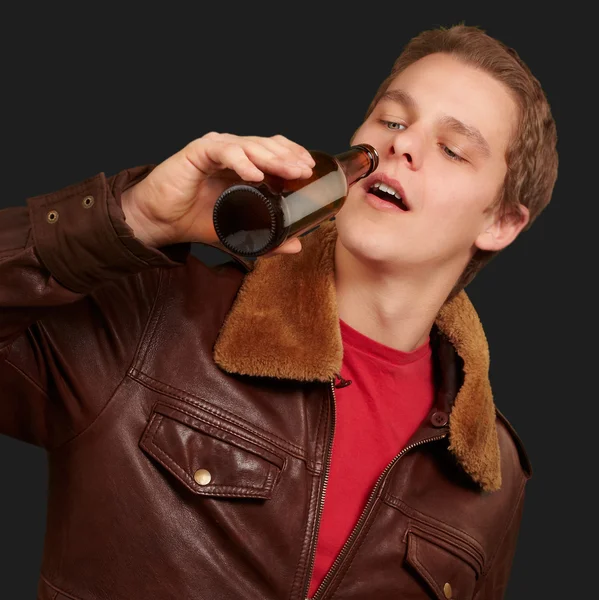 Retrato de jovem bebendo cerveja contra um fundo preto — Fotografia de Stock