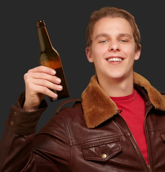 Portrait of young man holding beer on black background — Stock Photo, Image