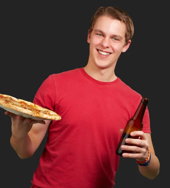 Portrait of young man holding pizza and beer over black backgrou — Stock Photo, Image