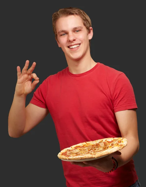 Портрет молодого человека, держащего пиццу и делающего добрый жест — стоковое фото