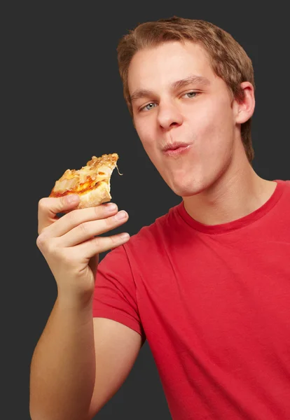 젊은 사람을 먹는 피자 부분 블랙 backgorund 이상의 초상화 — 스톡 사진
