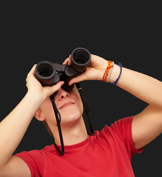 Portrait of young man with binoculars over black background — Stock Photo, Image