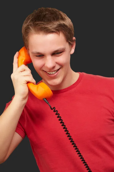 Portrait of young man talking on vintage telephone over black ba — Stock Photo, Image