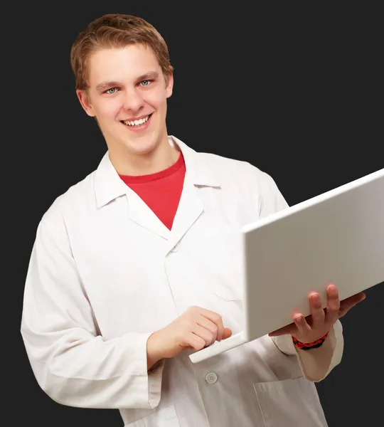 Portrait de jeune étudiant tenant un ordinateur portable sur fond noir — Photo