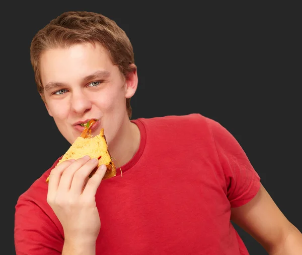 Retrato de jovem comendo pizza sobre fundo preto — Fotografia de Stock
