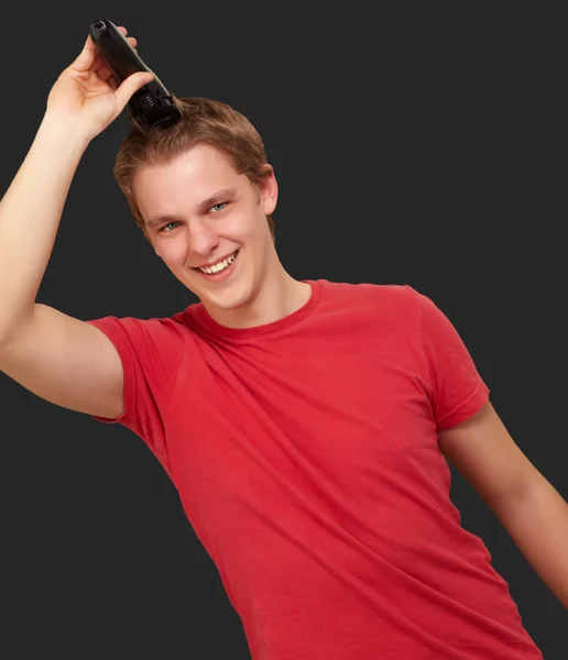 Porträtt av ung man klippa sitt hår över svart bakgrund — Stockfoto