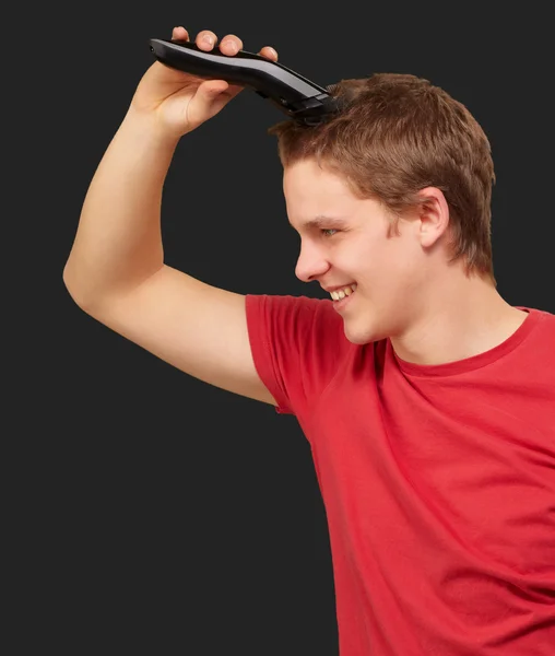 Portrait de jeune homme coupant ses cheveux sur fond noir — Photo