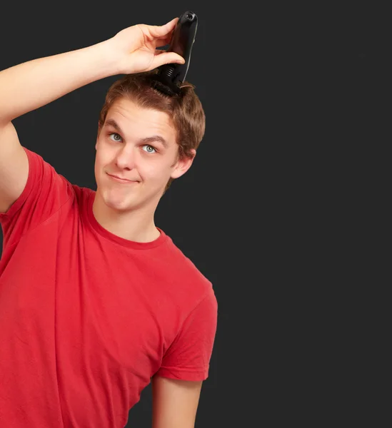 Portrait of young man cutting his hair over black background — Stock Photo, Image