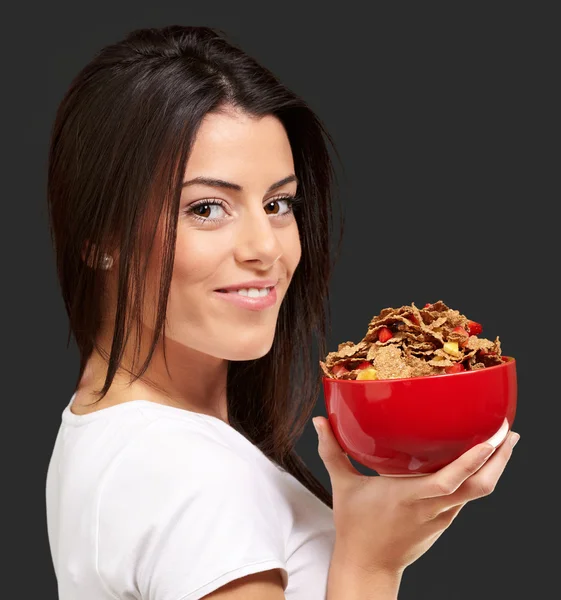 Portrait of young woman holding a cereal bowl over black backgro — Stock Photo, Image