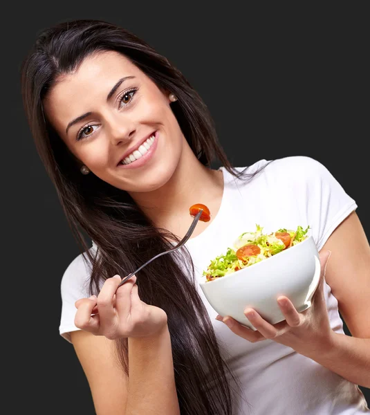 Портрет здоровой женщины, поедающей салат против черной спинки — стоковое фото
