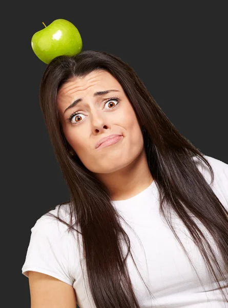Retrato de una mujer joven sosteniendo manzana verde en su cabeza sobre bla —  Fotos de Stock